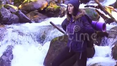 女游客站在靠近山河的树林里的一块石头上，慢悠悠地